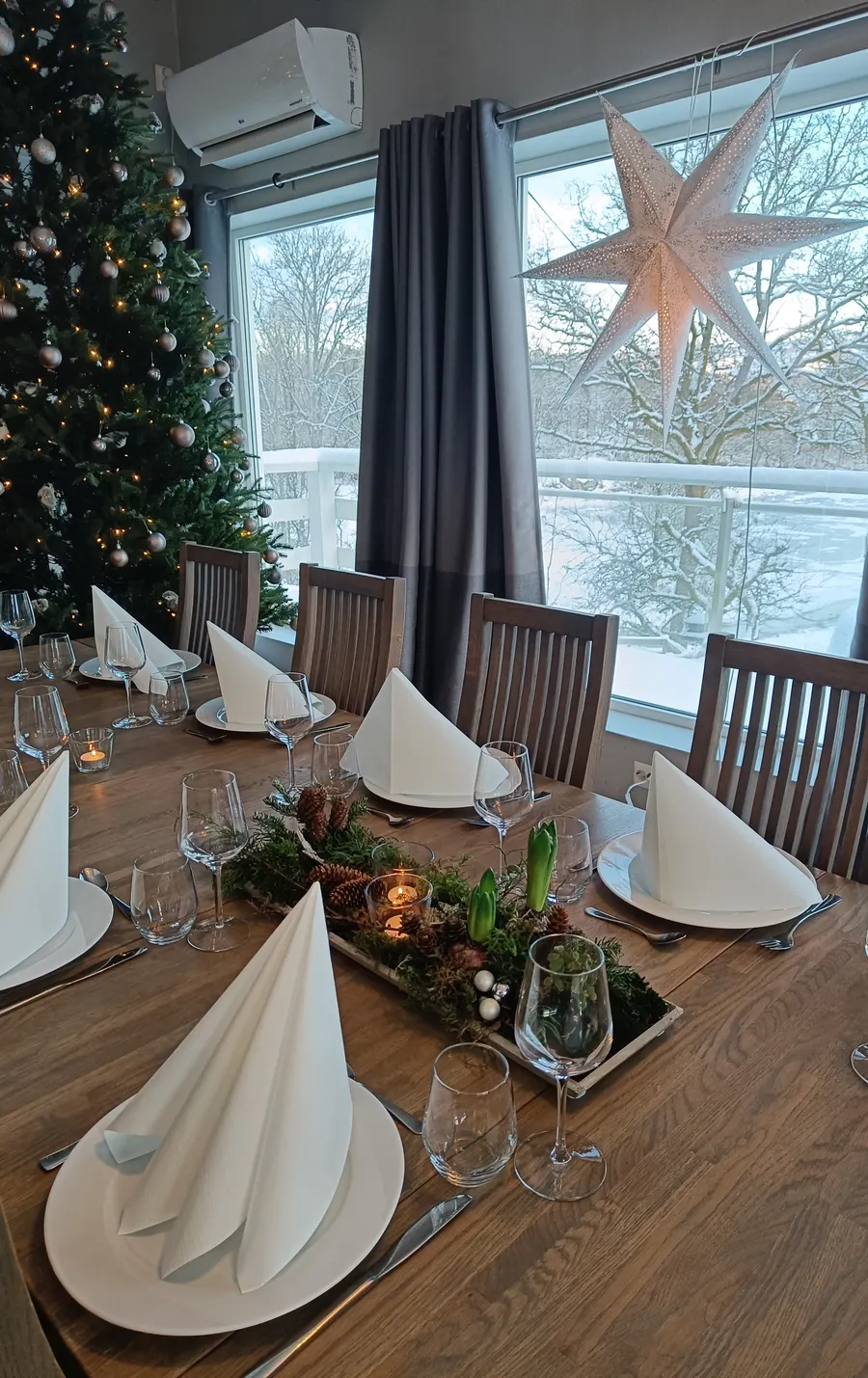 Dekket julebord med adventsstjerne i vinduet og snø utenfor