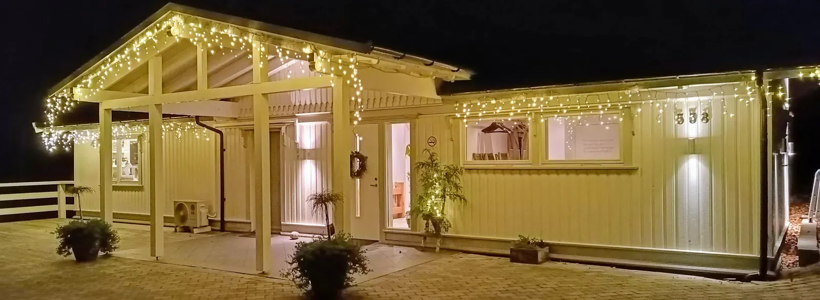 Verkstaden med julelys langs takskjegget en desemberkveld